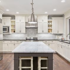 a large kitchen with white cabinets and an island