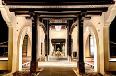 an entrance to a building at night with lights on and columns in the front yard