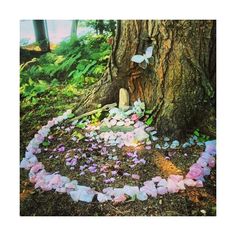 butterflies are scattered around the base of a tree in a forest with pink and white flowers