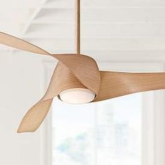 a wooden ceiling fan hanging from the ceiling in a room with white walls and windows