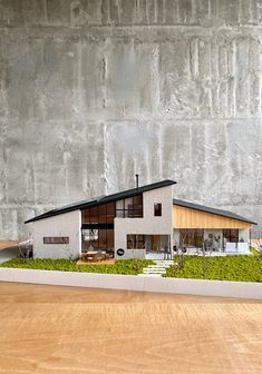 a model of a house sitting on top of a wooden table next to a wall