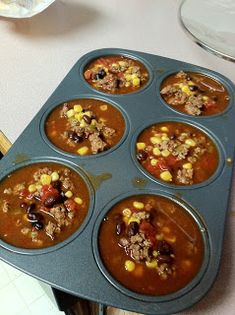 a muffin tin filled with lots of food sitting on top of a white table