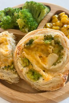 broccoli, corn and cheese wrapped in bread on a wooden plate with a spoon