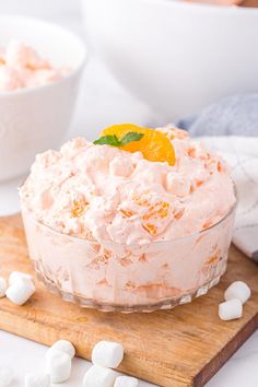 a bowl filled with food sitting on top of a wooden cutting board next to marshmallows