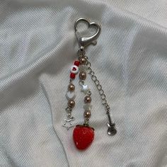 a heart shaped keychain with charms attached to it on a white fabric background