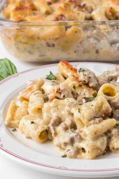 a white plate topped with pasta covered in meat and sauce next to a casserole dish