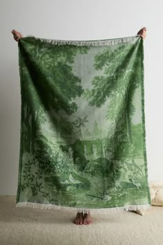 a person holding up a green and white tapestry