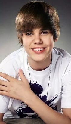 a young boy is posing for a photo with his hands on his chest and smiling at the camera