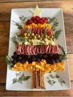 a christmas tree made out of fruits and cheeses on a white plate with rosemary sprigs