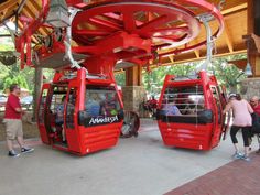 two red trolleys parked in front of a building with people standing around them and talking