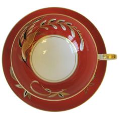 a red and white bowl with gold trimmings on the rim is sitting in front of a white background