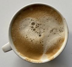 a white cup filled with liquid on top of a table