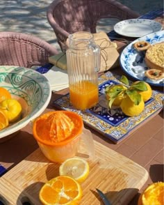 oranges and lemons are on the table with plates, cups and utensils