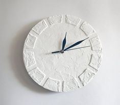 a white clock with blue hands on a wall