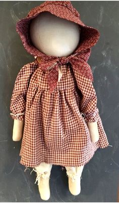 the doll is wearing a red and white checkered dress with a hood on it's head