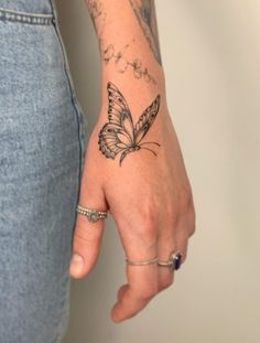 a woman's hand with a butterfly tattoo on her left wrist and the other arm