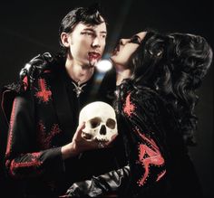 a man and woman kissing while holding a skull