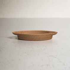 a woven basket sitting on top of a white table next to a black object in the background