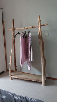 clothes hanging on a wooden rack in a bedroom