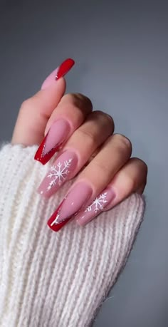 a woman's hand with red and white nail polish on it, while she is holding