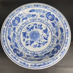 a blue and white bowl with flowers on the rim is sitting on a gray surface