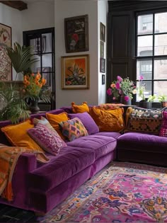 a living room filled with purple couches and lots of colorful pillows on top of it