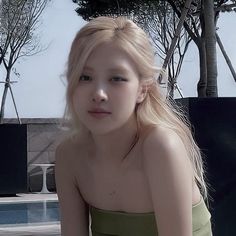 a woman in a green dress sitting next to a swimming pool