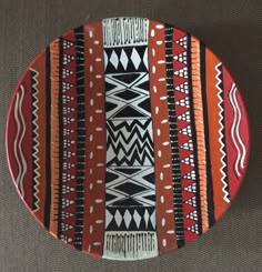 an orange and black plate with designs on the bottom is sitting on a gray surface