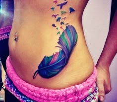 a woman's stomach with a colorful feather tattoo on her belly and butterflies flying out of it