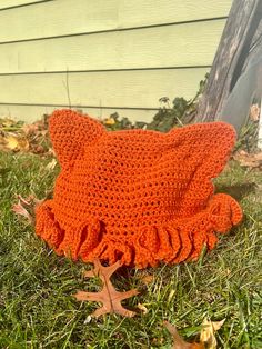 an orange crocheted hat laying on the grass