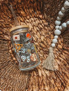 a glass jar sitting on top of a table next to a string of beads and a tassel