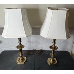 two lamps sitting on top of a table next to each other, one with a white shade