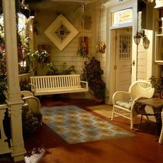 the porch is decorated with wicker furniture and potted plants on either side of the door