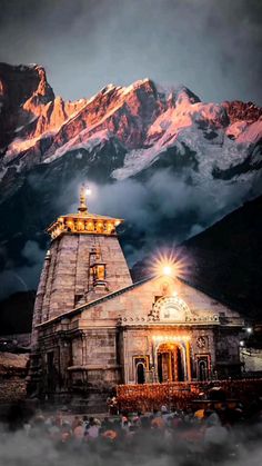 an old temple in front of a mountain range at night with lights shining on it