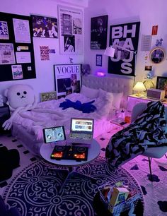 a bedroom with two laptops on the table and pictures on the wall behind it