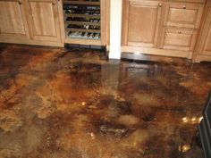 a dirty kitchen floor with brown stains on the top and bottom floors, in front of wooden cabinets