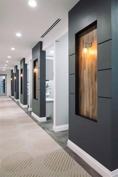 the hallway is lined with gray and white walls, along with modern lighting fixtures on either side