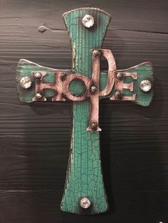 a wooden cross with the word hope painted on it and rivets in the center