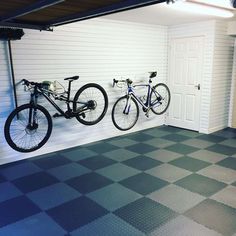 two bikes hanging on the wall in a garage with checkered flooring and white walls