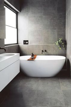 a large white bath tub sitting next to a sink in a bathroom under a window