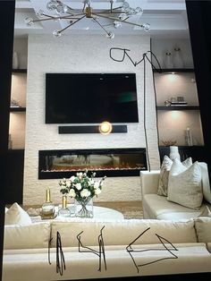 a living room with white couches and a flat screen tv mounted on the wall