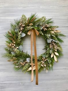 a christmas wreath hanging on the side of a wooden wall with greenery and pine cones