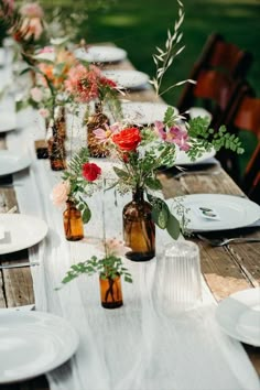 a long table with plates and vases filled with flowers