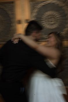 a man and woman dance together in front of a wall with art work on it