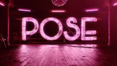 a neon sign that says pose in the middle of a room with wooden floors and purple lighting