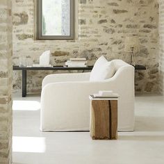 a living room filled with furniture and a table in front of a brick wall that has a window