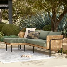 a couch sitting on top of a white rug in front of a green plant filled garden