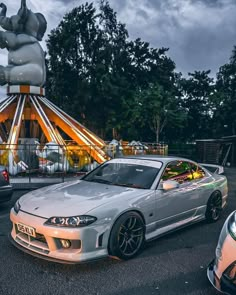 two cars parked next to each other in front of a merry - go - round