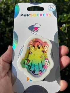 a person holding up a small sticker in front of a box with the word popsockets on it