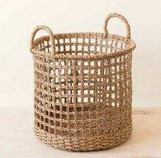 a woven basket sitting on top of a wooden table next to a white wall and floor